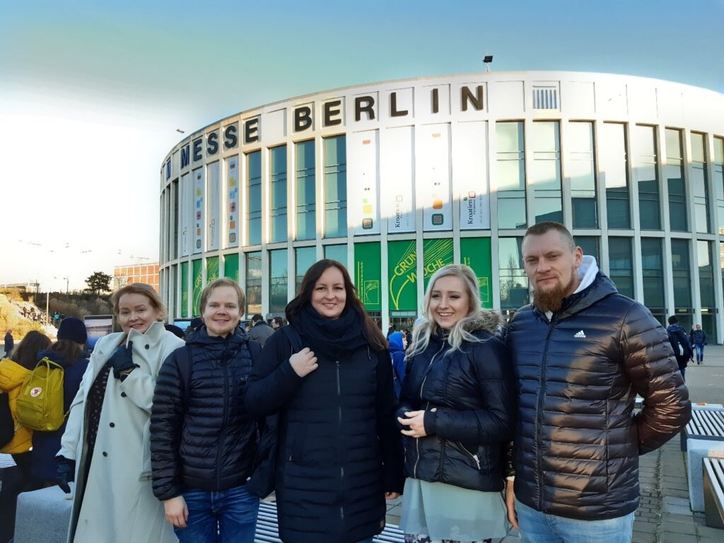 Neljä ihmistä seisoo Berliinin messuhallin edessä.
