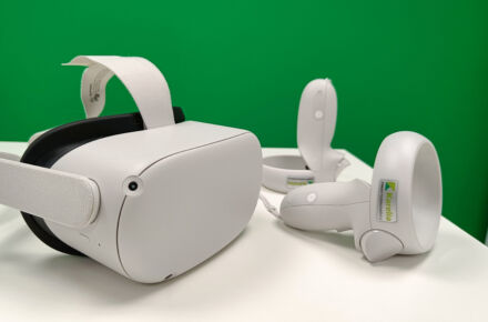 Valkoisella pöydällä on Quest 2 -virtuaalilasit sekä se laitteen kaksi käsiohjainta.