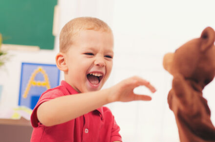 Lapsi nauraa käsinukelle (artikkelikuva)