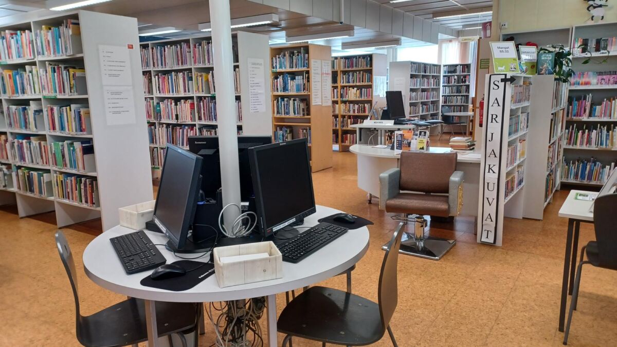 Kuva kirjastotilasta, jossa kirjahyllyjä ja tietokoneita