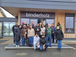 A group of people posing for a photo in front of a Binderholz building.